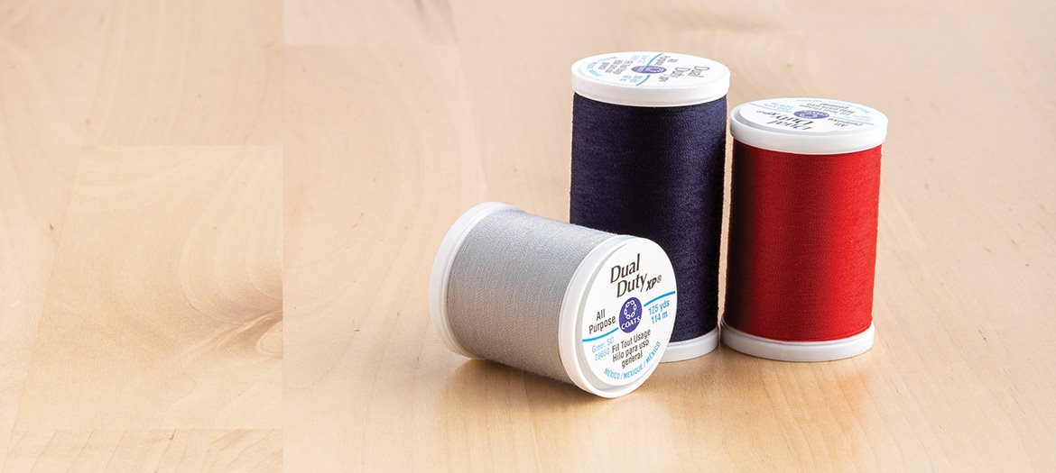 Coats Dual Duty XP Thread Black, Red and Grey Spools on Table for hand sewing or machine sewing