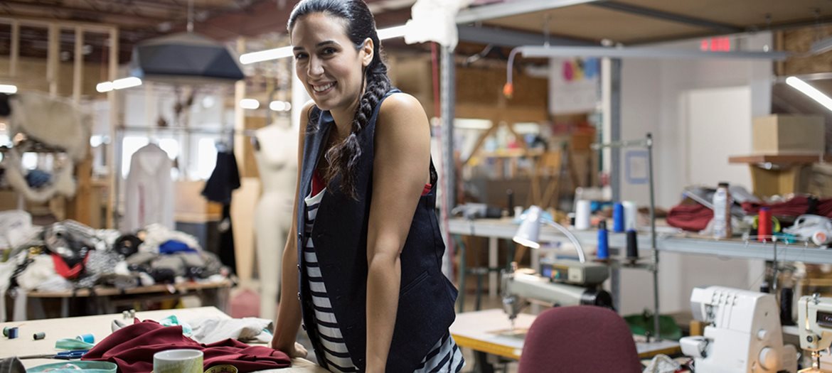 Woman in Industrial Sewing Space with Sewing Machines Fabric and Supplies